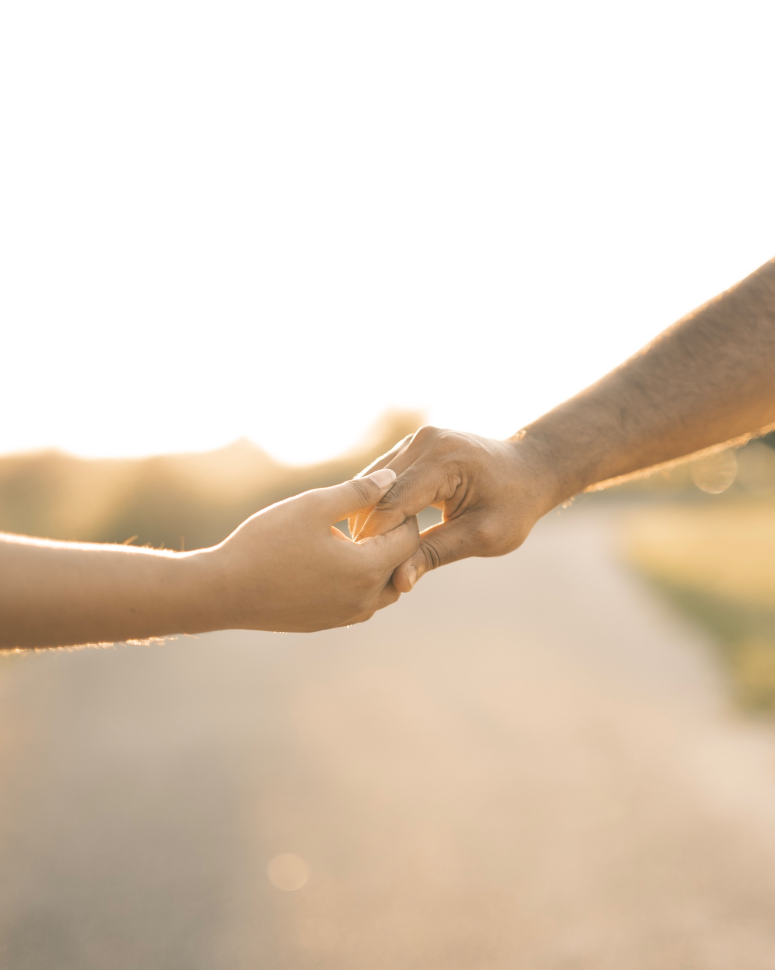 Two hands intertwined at sunset