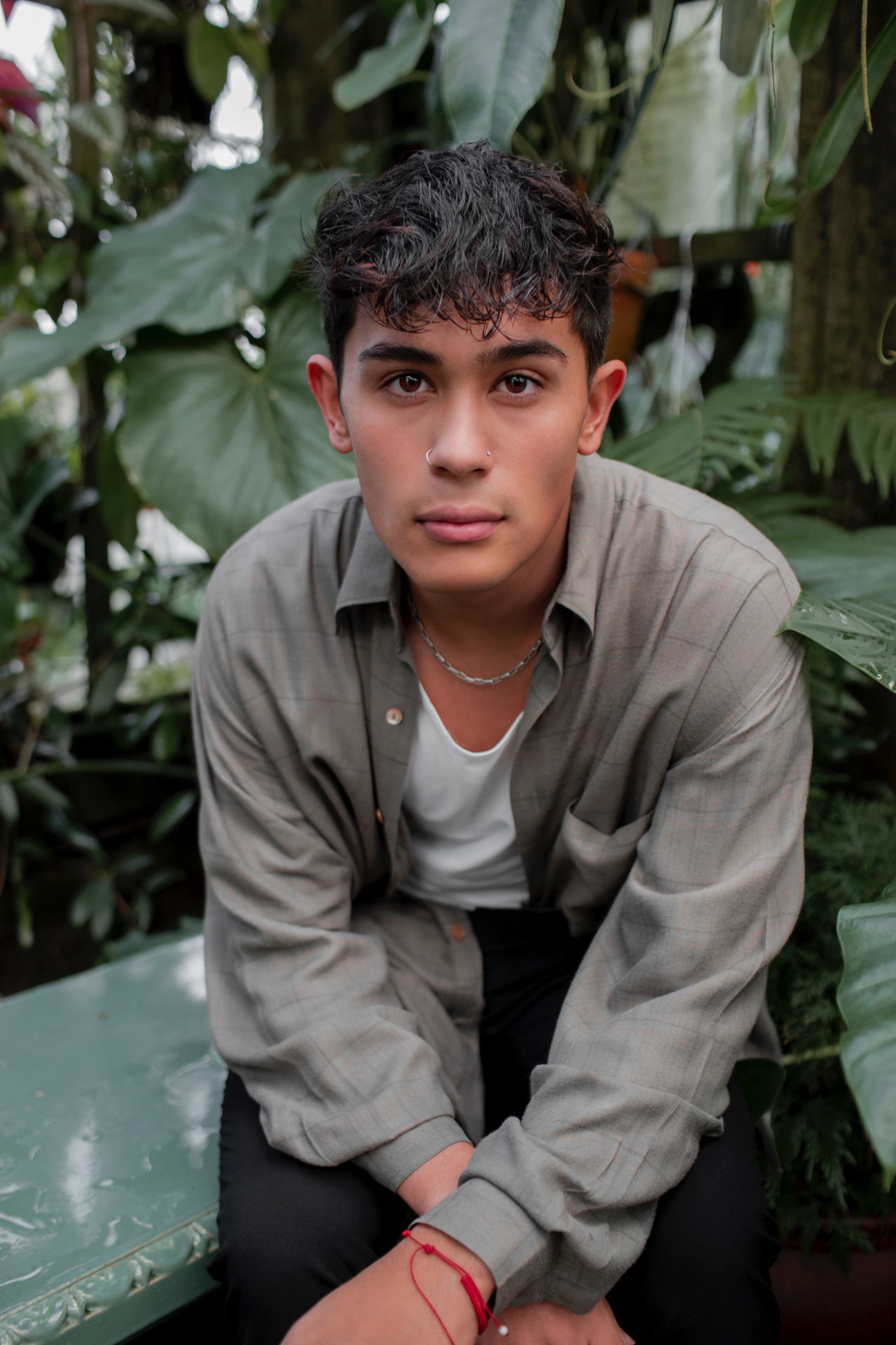 Portrait seated among lush greenhouse foliage
