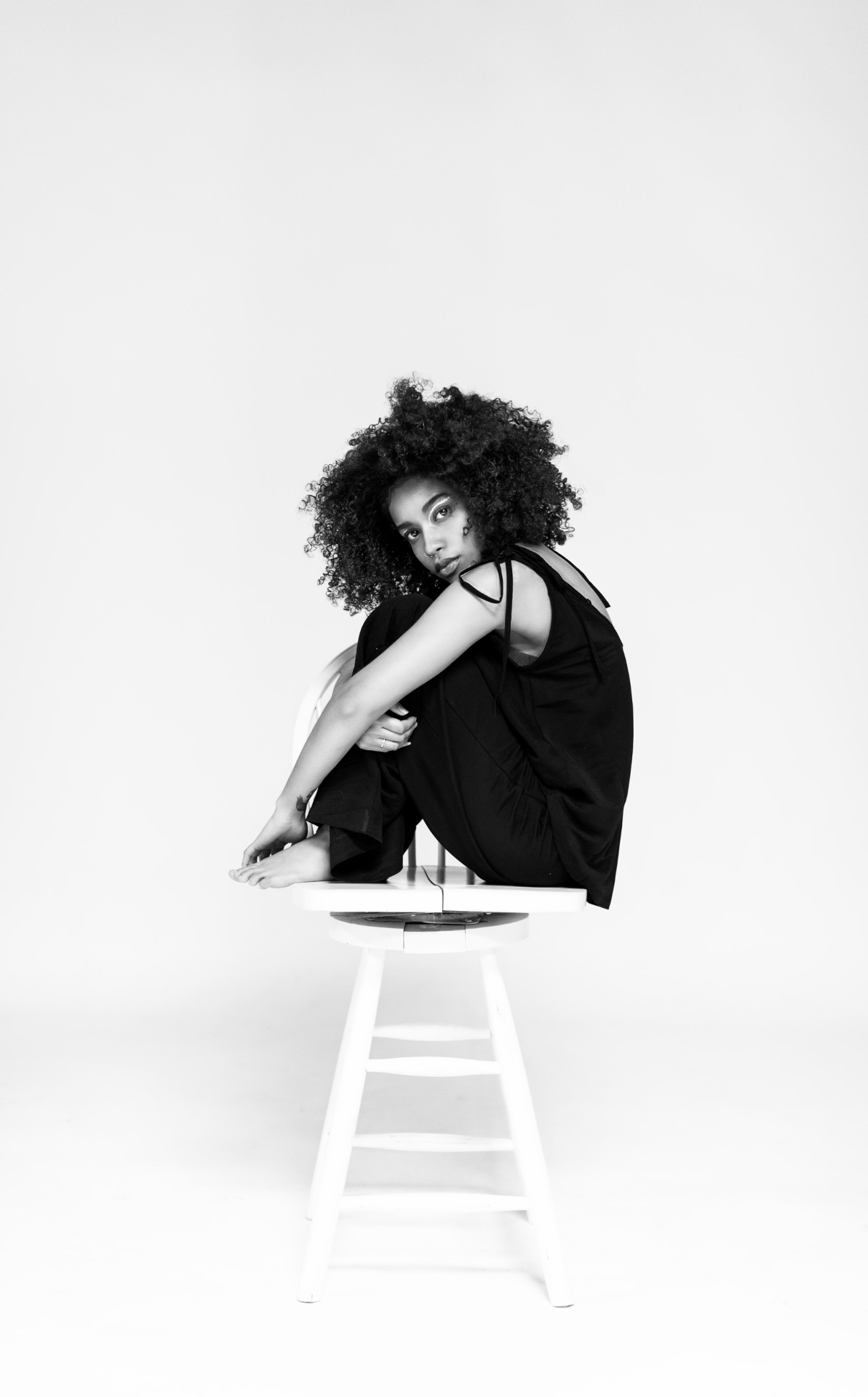 Black-and-white studio portrait of a woman seated on a stool