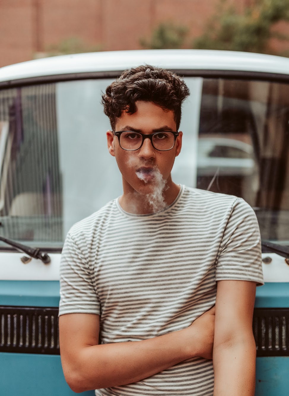 Portrait of a man in glasses leaning against a vintage van