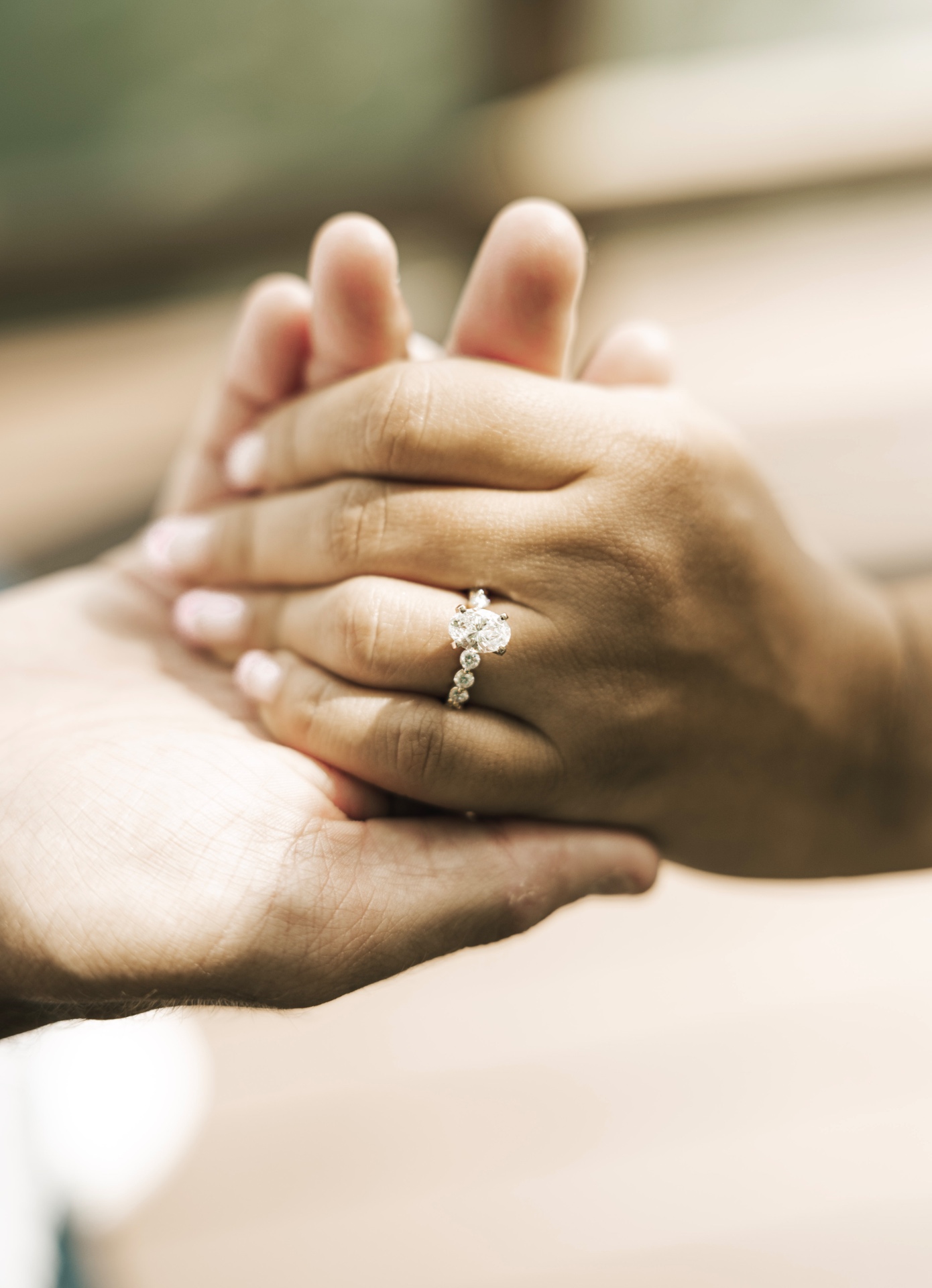 Close-up of an engagement ring on clasped hands